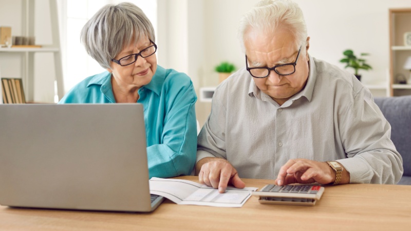 Coppia di anziani con computer e calcolatrice